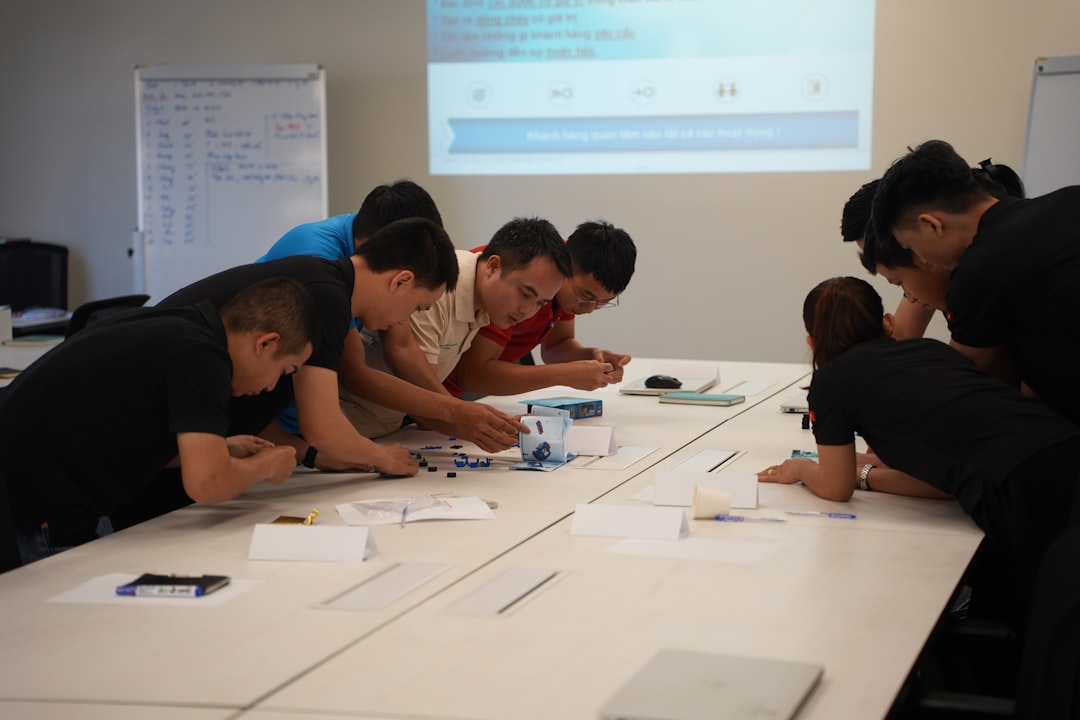 Team collaborating on a project at a table. team discussing api workflow, whiteboard planning, software development meeting