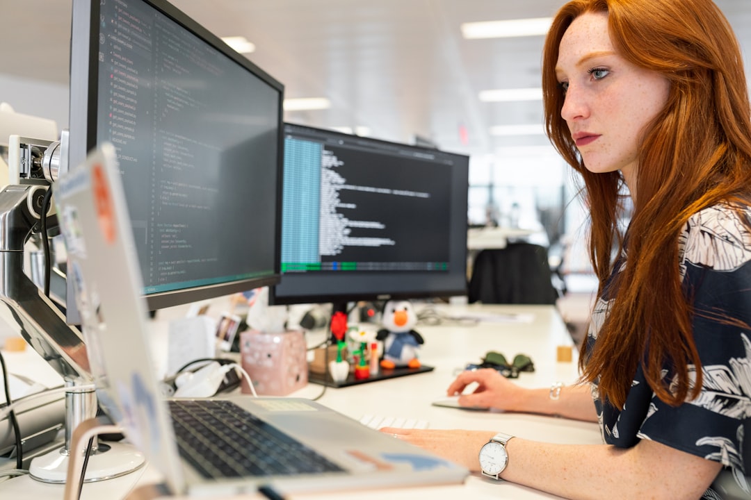 woman in green shirt sitting in front of computer software team, remote collaboration, source code