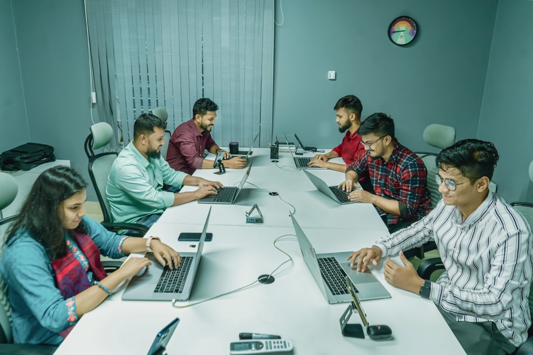 a group of people sitting around a table with laptops cybersecurity team meeting, digital evidence review, incident response planning