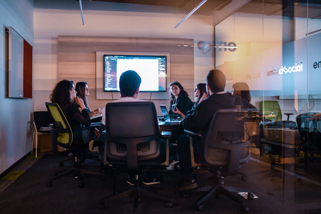 a group of people sitting in chairs in front of a projector screen business team virtual meeting secure connection lock icon digital interface