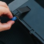 a hand holding a black rectangular object removing laptop battery power reset process