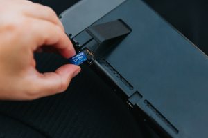 a hand holding a black rectangular object removing laptop battery power reset process