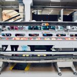 a large white machine with orange balls robotic sorting system, warehouse conveyor robots, package sorting automation