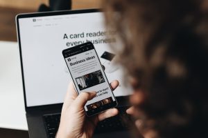 A person holding a cell phone in front of a laptop newsletter design, mobile email, ecommerce sales, automation flow