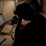 a person sitting in front of a laptop computer stressed student, messy desk, laptop at night
