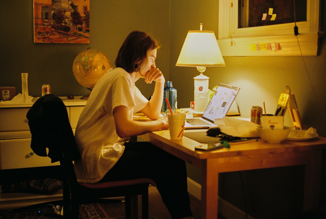 a woman sitting at a desk with a laptop stressed student, messy desk, laptop at night