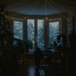 Cozy room with fairy lights and snowy window view. essential oil diffuser, cozy living room, soft lighting, indoor plants