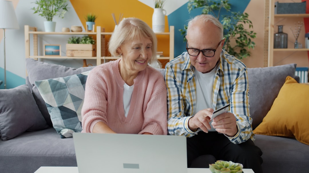 Elderly couple using laptop and credit card at home online doctor appointment laptop, digital health dashboard, modern living room