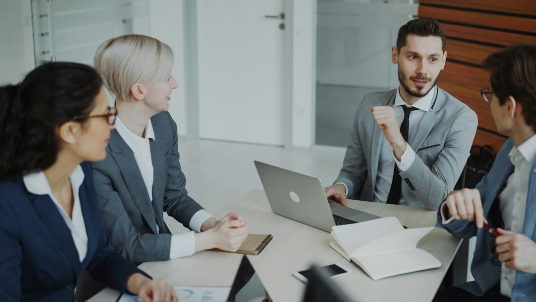 Four professionals in a business meeting around a table kpi report, engagement metrics, executive meeting