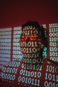 man in black and white checkered shirt cyber attack illustration, hacker at computer, red warning screen