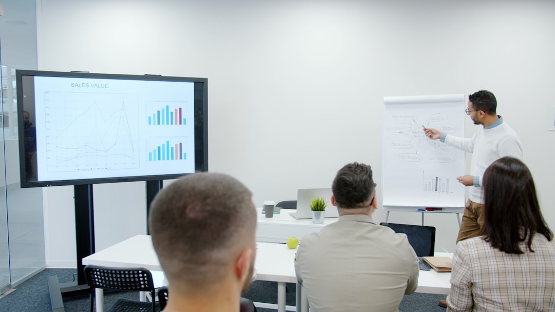 Man presents charts to seated audience in a modern office. employee training session, digital documentation workshop, team presentation screen