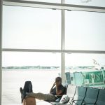 Man talking on phone in airport waiting area traveler swapping sim card, smartphone close up, airport setting