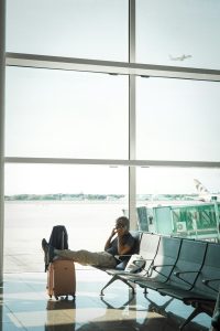 Man talking on phone in airport waiting area traveler swapping sim card, smartphone close up, airport setting