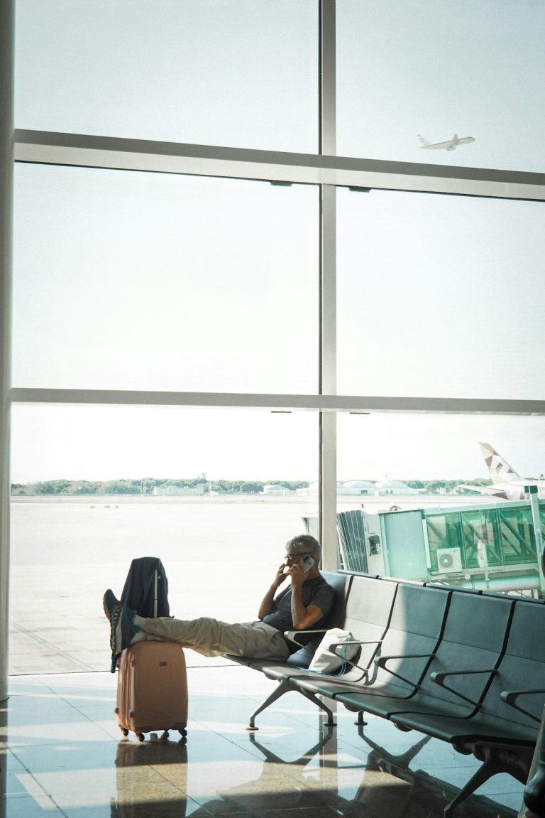 Man talking on phone in airport waiting area traveler swapping sim card, smartphone close up, airport setting