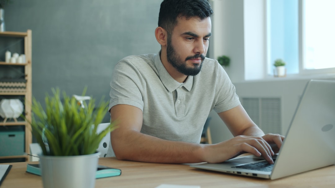 Man typing on a laptop at a desk. person working from home, laptop healthcare coding, home office workspace, relaxed professional