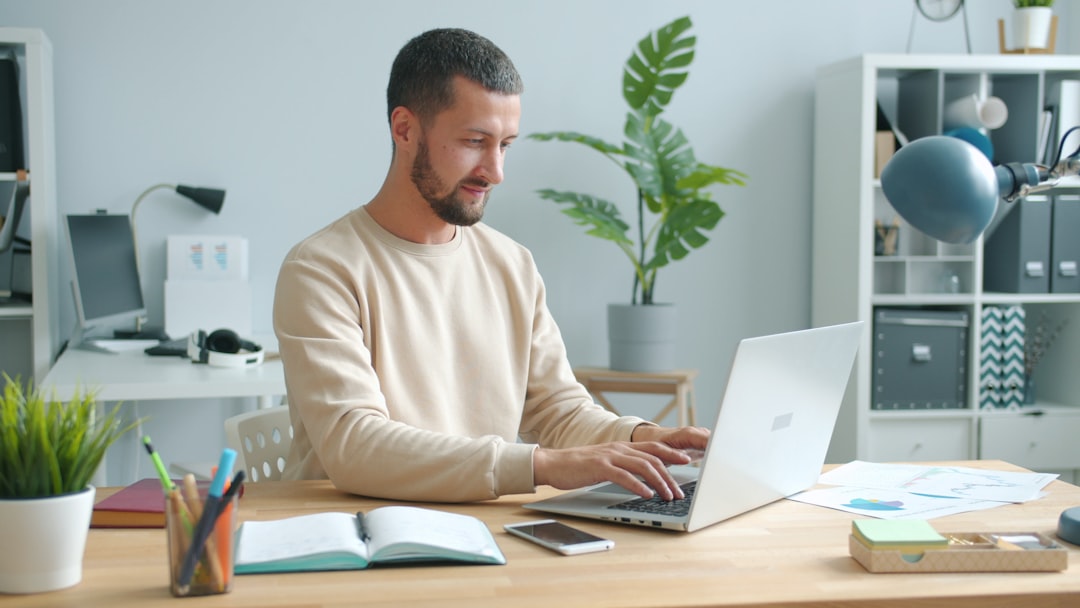 Man typing on laptop at a desk person working from home, laptop healthcare coding, home office workspace, relaxed professional