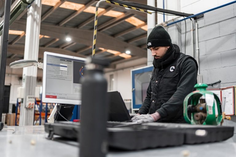 Man works on a computer in a manufacturing setting. technician wearing smart glasses, augmented reality interface, industrial maintenance environment