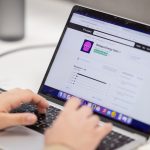 Person typing on a laptop computer screen. digital asset dashboard, brand management interface, content library screen