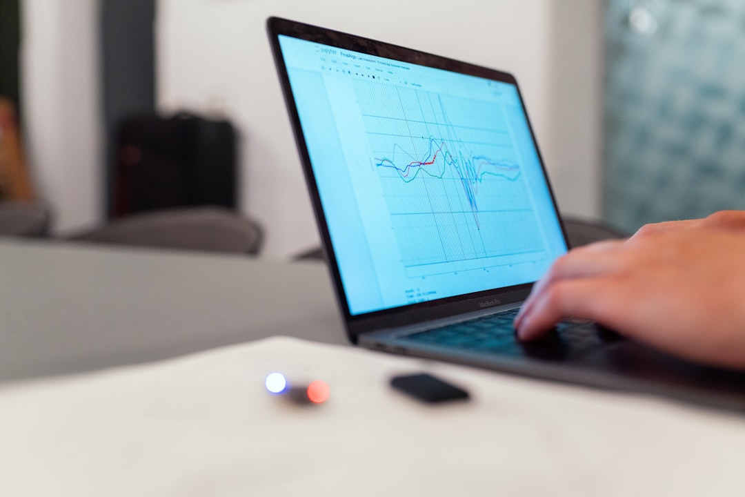 person using black laptop computer person working on laptop with savings chart, piggy bank, upward arrow graph