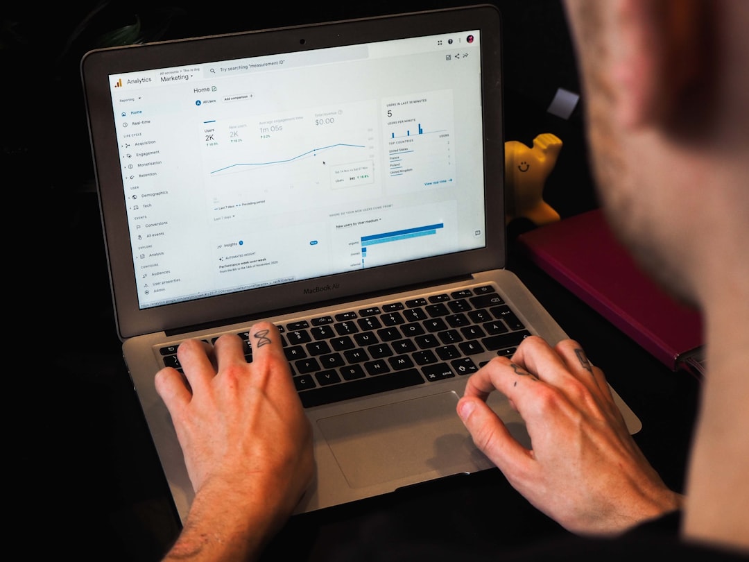 person using macbook pro on black table keyword ranking chart laptop seo report
