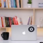 silver macbook on white table remote work setup laptop security shield icon office environment