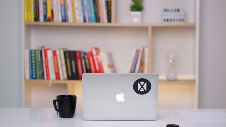 silver macbook on white table remote work setup laptop security shield icon office environment