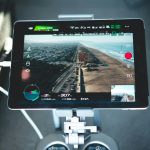 turned-on drone LED monitor drone pilot reviewing tablet, flight analytics dashboard, team meeting with drone data