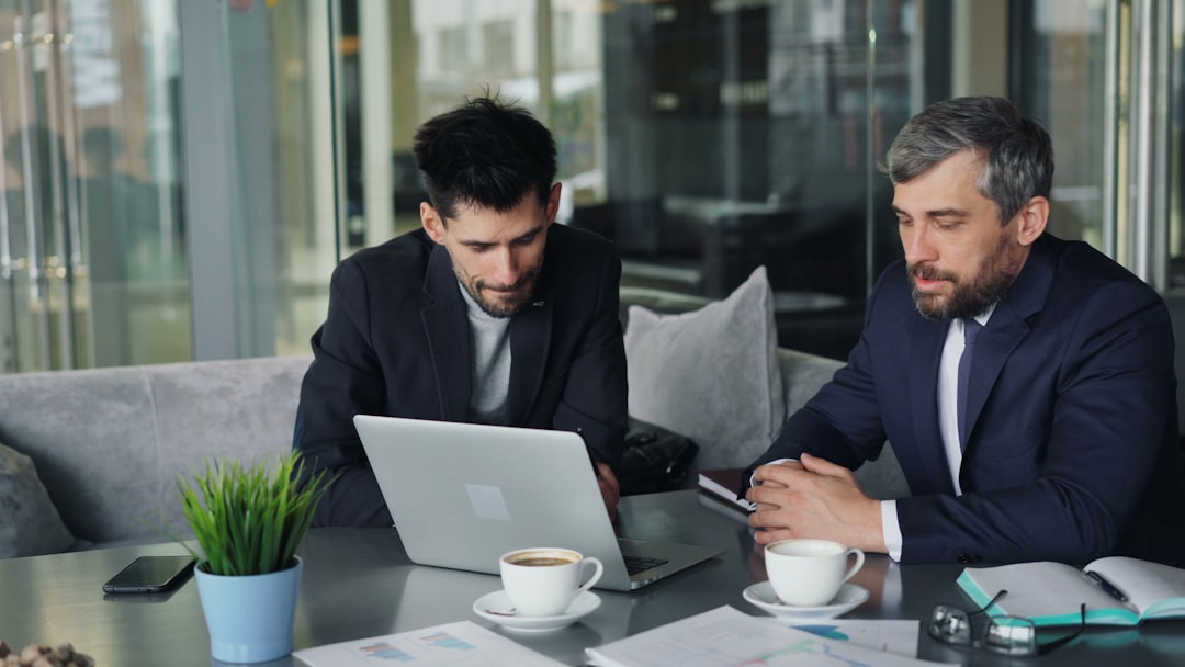 two men sitting at a table looking at a laptop lawyers reviewing documents on laptop, cloud technology, legal collaboration