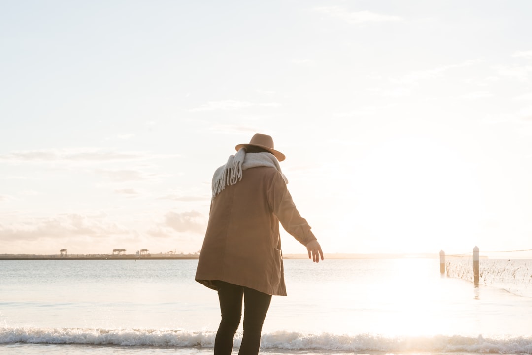 woman standing on shore during golden hour middle aged woman walking beach at sunset, peaceful ocean background, reflective mood