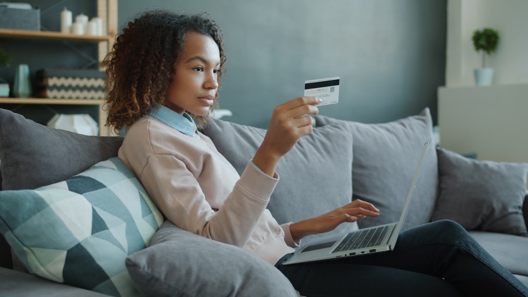 Woman using laptop and credit card on sofa happy customer using laptop credit card online subscription payment