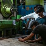 Workers operating heavy machinery in a factory. manufacturing floor, production planning, inventory software