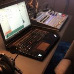 a laptop computer sitting on top of a desk music production studio laptop headphones audio editing screen
