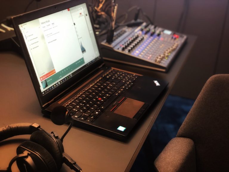 a laptop computer sitting on top of a desk music production studio laptop headphones audio editing screen