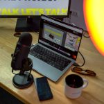 a laptop computer sitting on top of a wooden desk podcast microphone laptop headphones desk setup