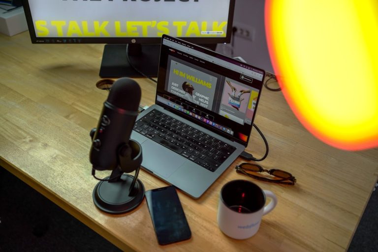 a laptop computer sitting on top of a wooden desk podcast microphone laptop headphones desk setup