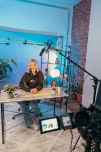 a person sitting at a table professional streaming studio, camera microphone lighting, control desk, live broadcast environment