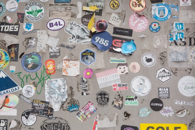 A wall covered in lots of different types of stickers custom stickers, product packaging, brand labels