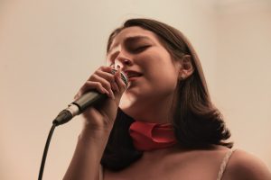 A woman sings into a microphone, eyes closed. singer posture, relaxed shoulders, vocal practice