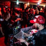 Dj playing music for a crowd at a party dj laptop performance, nightclub crowd, mixing software interface, colorful stage lights