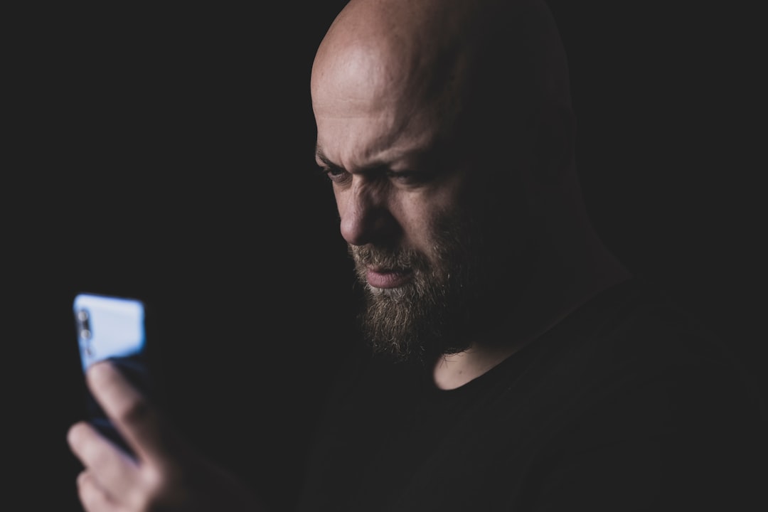 man in black crew neck shirt person receiving fraud alert on smartphone, security notification screen, worried expression