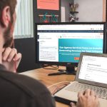 man sitting on chair using silver laptop artificial intelligence writing interface, laptop screen with blog draft, digital content creation workspace