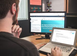 man sitting on chair using silver laptop artificial intelligence writing interface, laptop screen with blog draft, digital content creation workspace