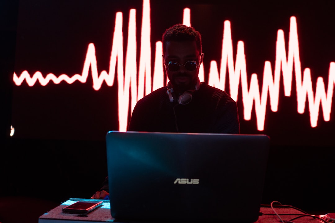 man standing in front Asus laptop virtual dj interface screen, waveform mixing display, home studio dj setup, laptop dj software