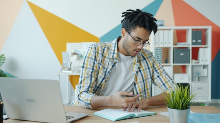 Man working at a desk with laptop and notebook. professional reviewing resume on tablet, modern office setting, career planning concept