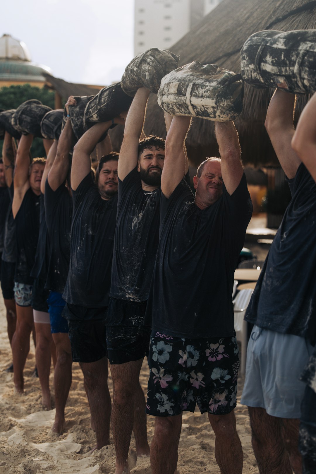 Men carrying heavy logs on a sandy beach team challenge, outdoor activity, coworkers solving clues, summer event