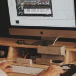 person using iMac computer set with digital piano application music production software interface, digital audio workstation screen, electronic music setup