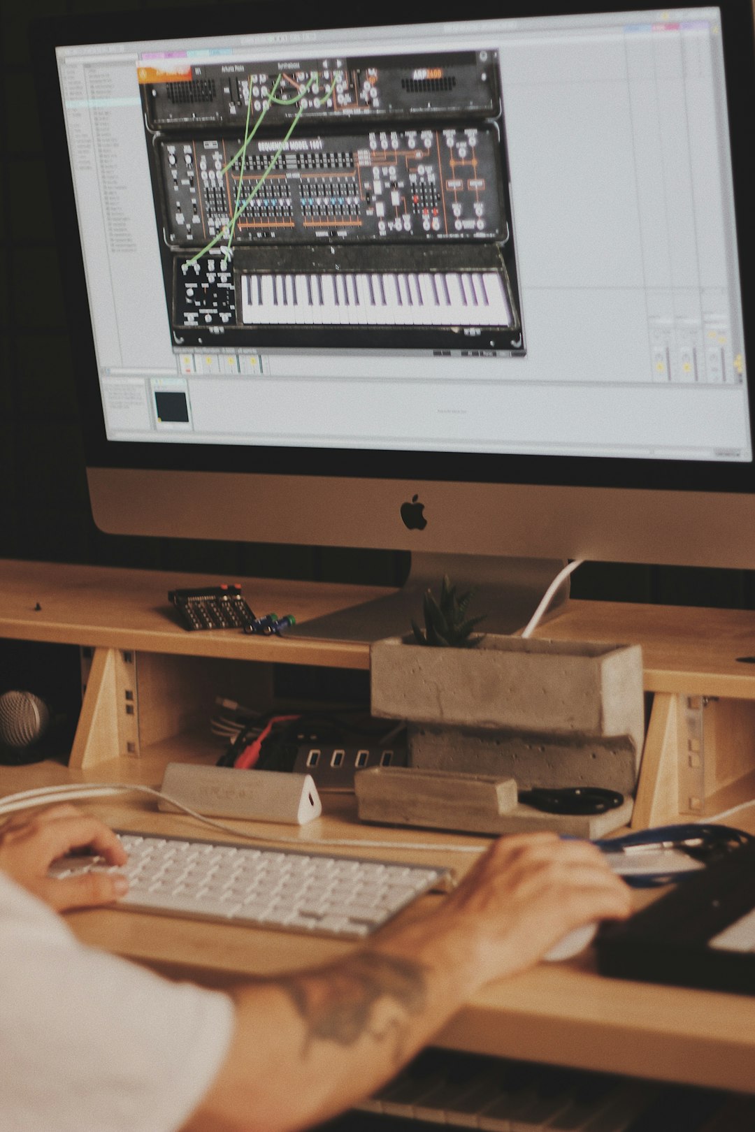 person using iMac computer set with digital piano application music production software interface, digital audio workstation screen, electronic music setup