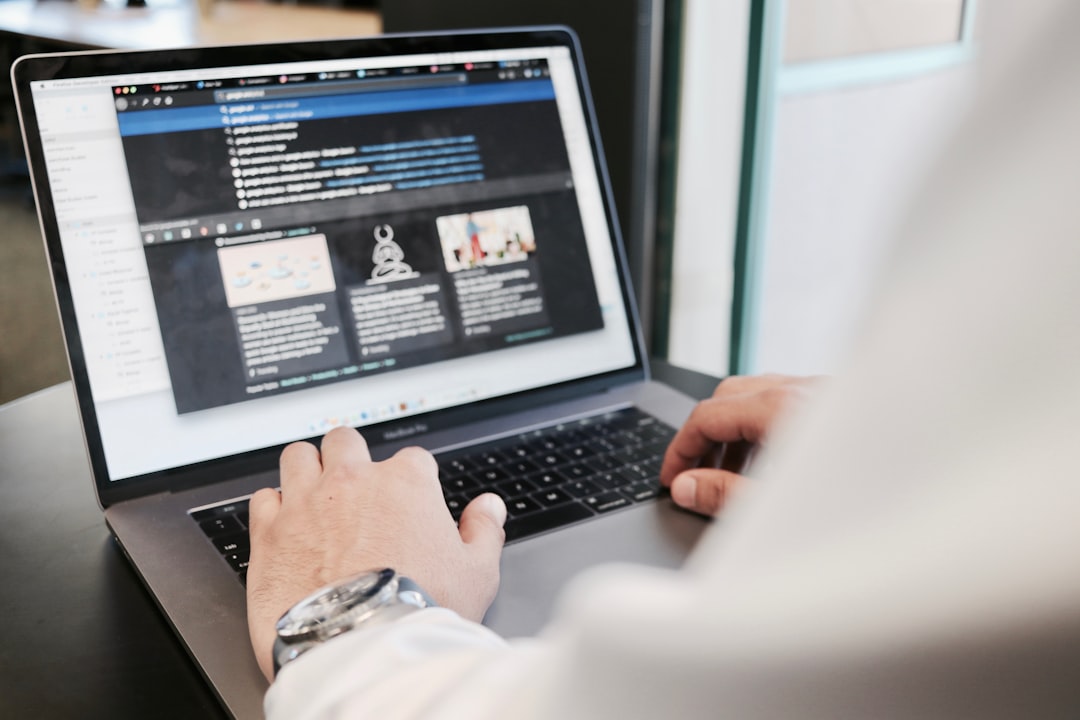 person using MacBook person editing article on laptop, review notes on screen, content optimization process