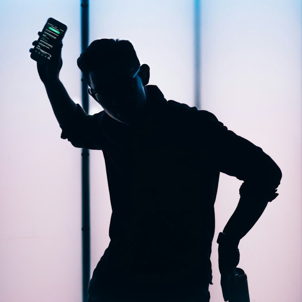 silhouette of man holding smartphone person receiving fraud alert on smartphone, security notification screen, worried expression