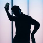silhouette of man holding smartphone person receiving fraud alert on smartphone, security notification screen, worried expression